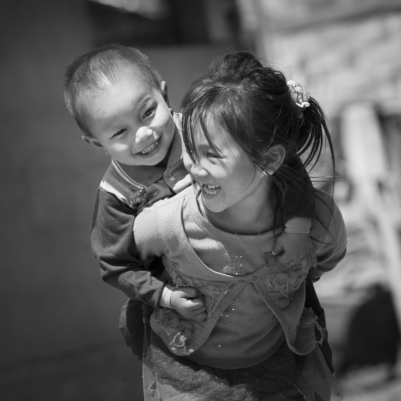 Dans un village Akha, à la frontière chinoise, une fillette porte son petit frère
