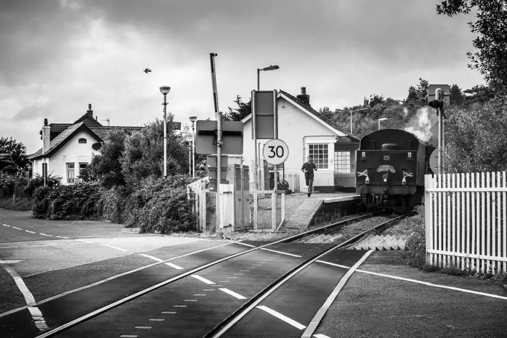 Train between Mallaig and Fort William. The railway worker has to run to close the railrod crossing.